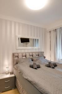 a white bedroom with a large bed with a mirror at Apartman Dolly Vrnjacka banja in Vrnjačka Banja +29 photos