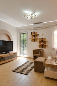 a living room with a flat screen tv and a couch at Apartman Dolly Vrnjacka banja in Vrnjačka Banja