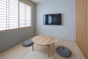a room with a table and a tv on a wall at GINNOYADO Main Location in Kyoto