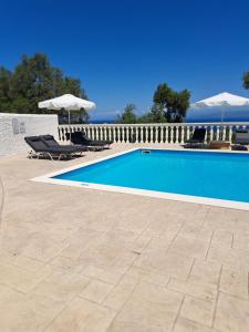 a swimming pool with chairs and umbrellas next to a fence at Villa Levanda (Loggos Paxos) in Longós