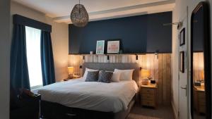 a bedroom with a large bed and a blue wall at Downs Hotel in Stanmer
