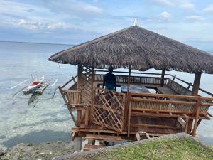 a person sitting on a bench under a straw umbrella at Sondol Guesthouse in Loon