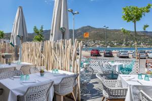a restaurant with tables and chairs with a view of a parking lot at Hotel Spa Porto Cristo in Port de la Selva