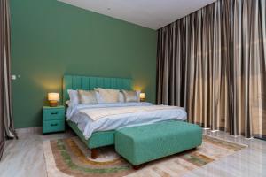 a bedroom with a green bed and a green ottoman at La villa Socé in Saly Portudal