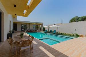 a swimming pool with a table and chairs next to a house at La villa Socé in Saly Portudal