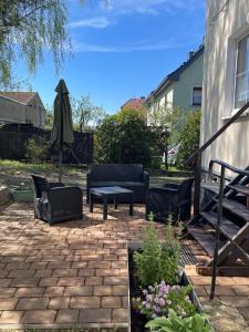een terras met een bank, een tafel en een parasol bij Ferienwohnung Am Wald in Großschönau