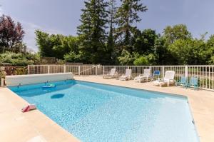a large swimming pool with chairs and a fence at Le gite du petit ecureuil in Balnot-sur-Laignes