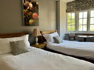 a bedroom with two beds and a table and a window at The Talbot and apartment in Iwerne Minster +1 photo