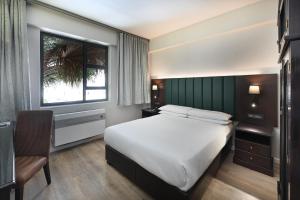 a bedroom with a bed and a window and a chair at ANEW Hotel Capital Pretoria in Pretoria