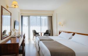a hotel room with two beds and a table at Odysseia Hotel Kapetanios in Limassol