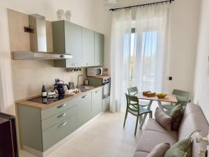 a kitchen with green cabinets and a table and a couch at Ti porto al mare - Luxury & Relax in Siracusa