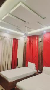 two beds in a room with red walls at Eastern Lodge Guest House in Dargai