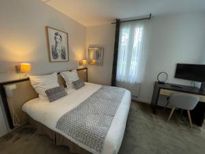 una camera da letto con un letto, una scrivania e una televisione di Adonis Cottage la Baule a La Baule