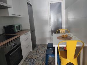 a small kitchen with a table and yellow chairs at Rusiñol in Consuegra