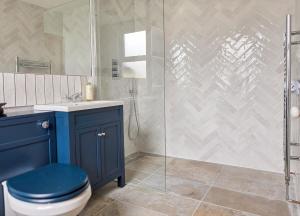 ein Badezimmer mit einem blauen WC und einer Glasdusche in der Unterkunft Cosy Cottage in Broadstairs in Broadstairs + 21 Fotos