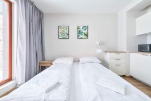 a white bedroom with a bed and a window at Waterlane Island Deluxe 5B by Grand Apartments in Gdańsk
