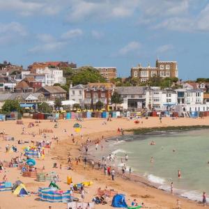 eine Gruppe von Menschen an einem Strand in der Nähe des Wassers in der Unterkunft Cosy Cottage in Broadstairs in Broadstairs