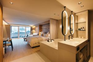 a bedroom with a bed and a sink and a mirror at Premium Activehotel Bergkönig in Neustift im Stubaital