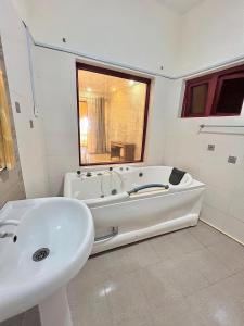 a white bathroom with a tub and a sink at Stunning beachfront 2 bedroom apartment in Mombasa