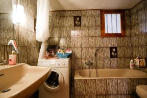a bathroom with a tub and a washing machine and a sink at Marousa's Country House 12 minutes from Athens Airport in Koropíon