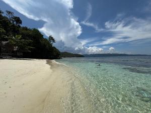 a beach with a person swimming in the water at Kring Kring Homestay in Yennanas Besir