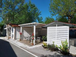 a white shed with a table and chairs on a patio at CAMPING CALATELLA parco di vacanza in Marina di Massa