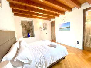 a bedroom with a large white bed with wooden ceilings at Wohnung Mit Privatem Garten Und Schöner Aussicht in Moniga