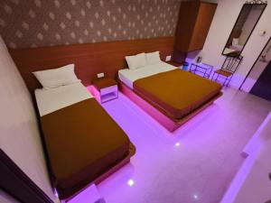 コールハープルにあるHotel Girija Residencyの紫色の照明が備わるドミトリールームのベッド2台 +10枚の写真