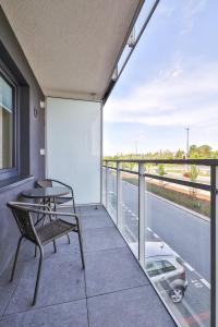 ワルシャワにあるPIleckiego 59 Studio z Balkonem Bezpłatny Parking By Perfect Apartのテーブルと椅子があり、通りの景色が見えるバルコニー