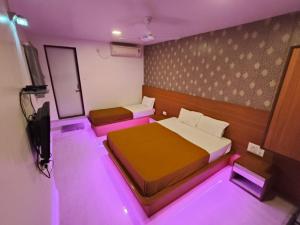 コールハープルにあるHotel Girija Residencyのベッド2台、テレビ、紫色の照明が備わる客室です。