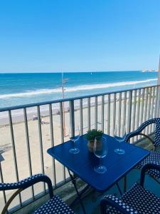 a table with wine glasses on a balcony with the beach at Nahia in Hendaye