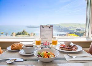 a table with breakfast food and a view of the ocean at Mevagissey Bay Hotel in Mevagissey