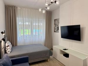 ein Schlafzimmer mit einem Bett, einem Fernseher und einer Couch in der Unterkunft City & Sea - Apartamenty i Mieszkania in Gdynia