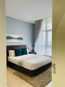 a bedroom with a large bed with blue pillows at iTowers Luxury Apartment in Gaborone