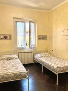 two beds in a room with a window at Le Crudi Home Genova Pegli in Genova