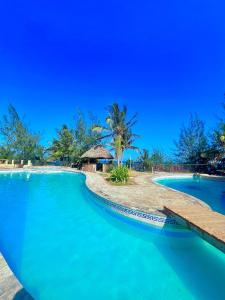 a resort swimming pool with a blue sky in the background at Stunning beachfront 2 bedroom apartment in Mombasa