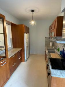 une cuisine avec des armoires en bois et un réfrigérateur en acier inoxydable dans l'établissement Sunny Escape - Cottage in Moudania Chalkidiki, à Nea Moudania