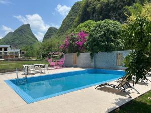 - une piscine avec une table, des chaises et des montagnes dans l'établissement Yangshuo Soul Resort-Beside Yulong River, à Yangshuo