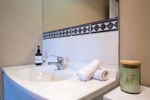 ein Waschbecken mit einer Flasche Seife und einem Spiegel in der Unterkunft Laneside - Akaroa Holiday Cottage in Akaroa + 8 Fotos