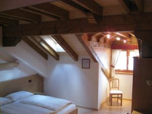 a bedroom with a bed and a chair in a attic at Affittacamere Alle Trote in Sùtrio