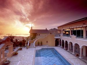 a villa with a swimming pool in front of a sunset at Yumihari-no-Oka Hotel in Sasebo