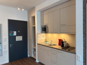 une cuisine avec des placards blancs et une porte bleue dans l'établissement Auszeit Urlaub mit Pflege, à Sankt Georgen im Schwarzwald
