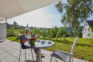 un homme assis à une table en train de lire un livre dans l'établissement Auszeit Urlaub mit Pflege, à Sankt Georgen im Schwarzwald