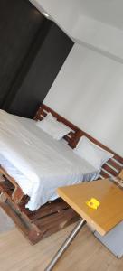 a bed with white sheets and a wooden table at DLF MyPad in Lucknow