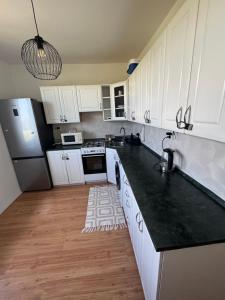 a kitchen with white cabinets and a black counter top at Krásný prostorný byt in Karviná +2 photos