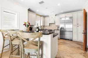a kitchen with white cabinets and a island with bar stools at Five Star in Inlet Beach