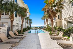a pool with chairs and palm trees next to a building at Five Star in Inlet Beach