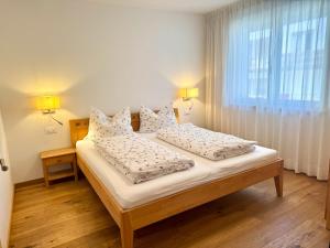 a bedroom with a bed with white sheets and a window at Ferienwohnungen Preiss in Schenna