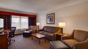 a hotel room with a couch and a tv at SureStay by Best Western Miles City in Miles City