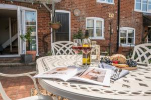 een tafel met een boek en glazen wijn bij Stable Cottage, Friston in Friston